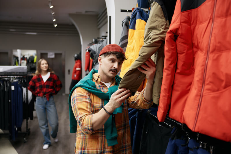 mężczyzna ogląda kurtki w sklepie
