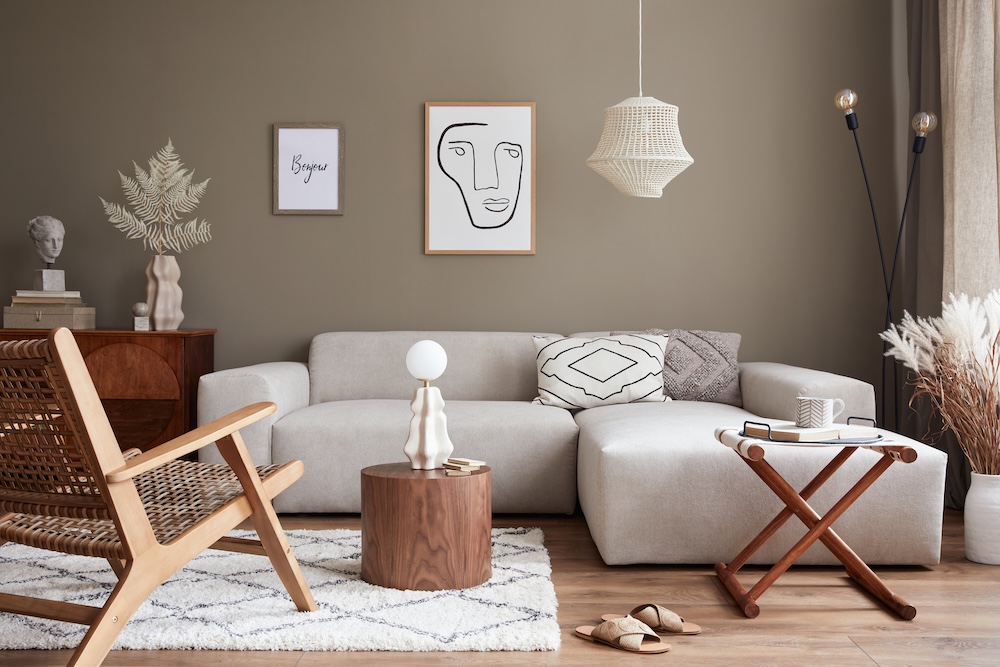 salon w stylu boho z meblami z drewna i jasną sofą na tle ściany w odcieniu ciemnego beżu 