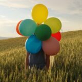 kolorowe balony jako element promocji podczas eventu osoba trzymająca kolorowe balony podczas wydarzenia plenerowego
