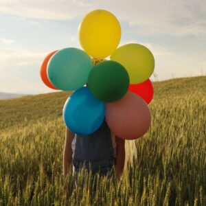 osoba trzymająca kolorowe balony podczas wydarzenia plenerowego