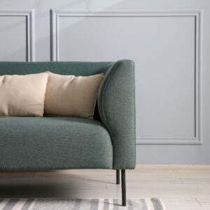 zielona sofa z beżowymi poduszkami w jasnym salonie